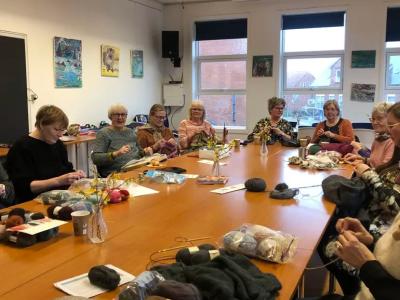 Deltagere ved håndarbejdscafé samlet om et bord med garn og håndarbejde